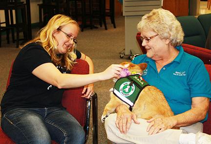 Malinda Ortlieb, left,  pets Nala while Nanci Kyhn, owner of Nala from healing Hearts Therapy Dogs, holds the small breed Corgi.